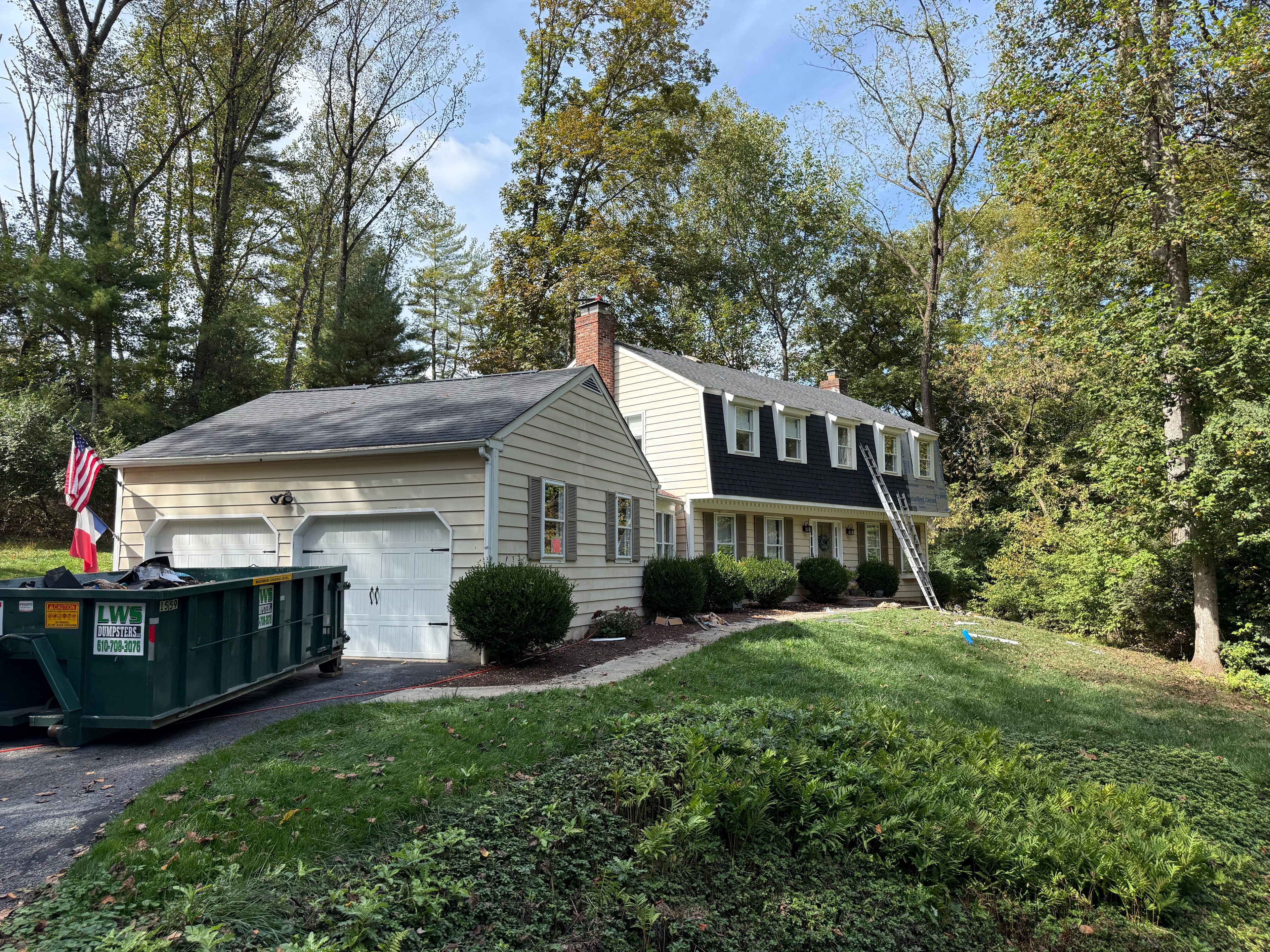Front of home with ladder against house and Moire Black shingles being installed