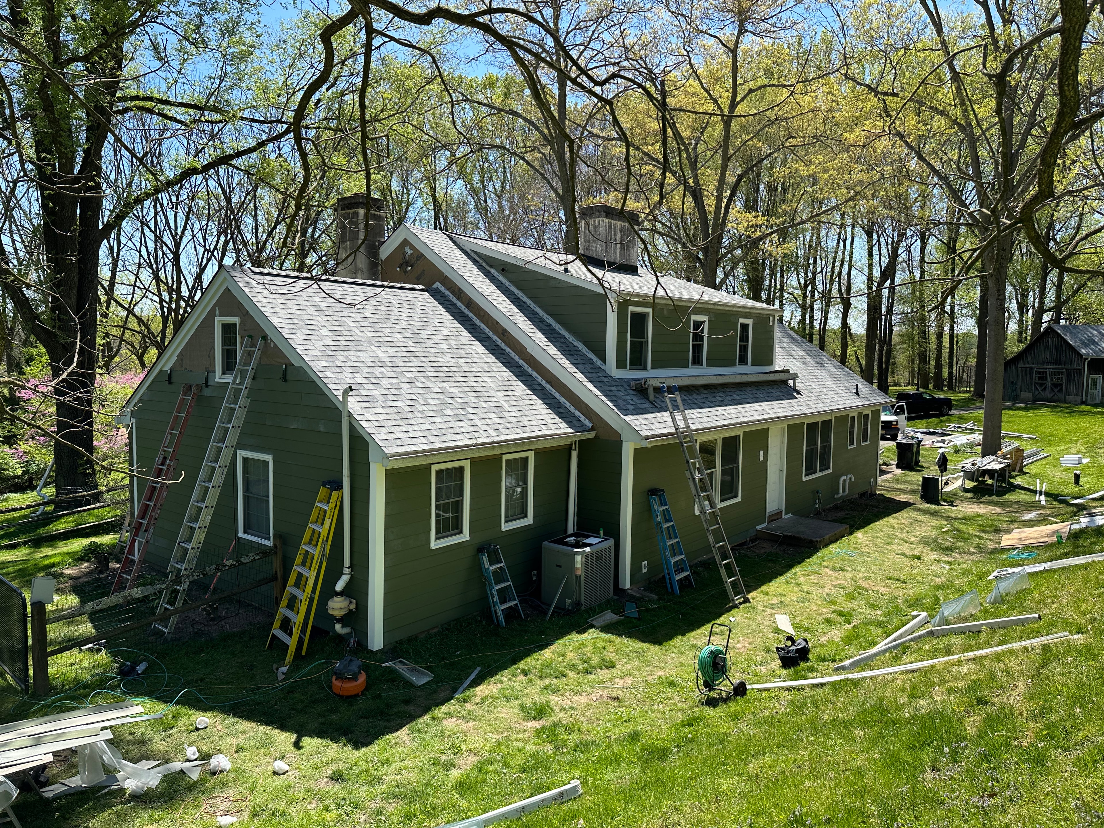 Aerial rear view of West Chester home with completed Sierra Grey roof and Mountain Sage Hardie siding, crew and ladders visible